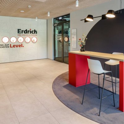 Empfangs- und Kommunikationsbereich mit Erdrich Logo und rotem Stehtisch